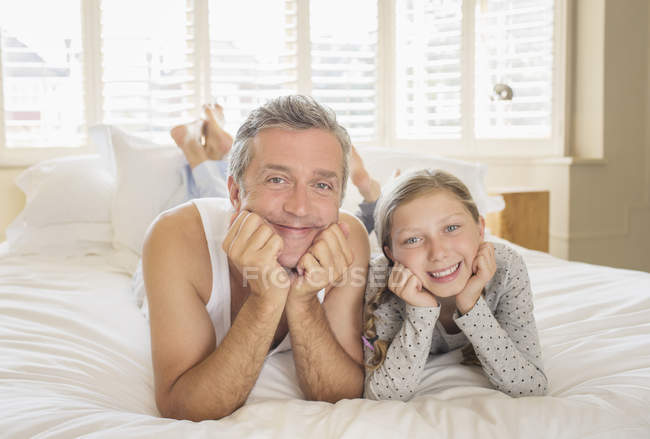 Padre e hija acostados en la cama - foto de stock
