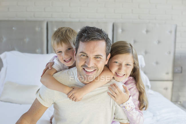 Padre e hijos abrazándose en el dormitorio - foto de stock