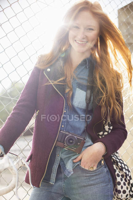 Счастливая молодая женщина, улыбающаяся через забор звена цепи — стоковое фото