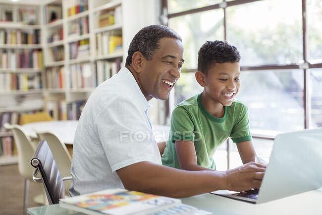 Abuelo y nieto usando laptop - foto de stock