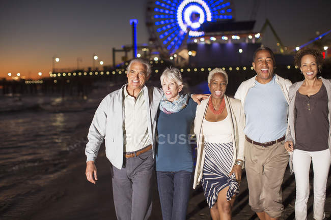 Amigos mayores caminando por la playa por la noche - foto de stock