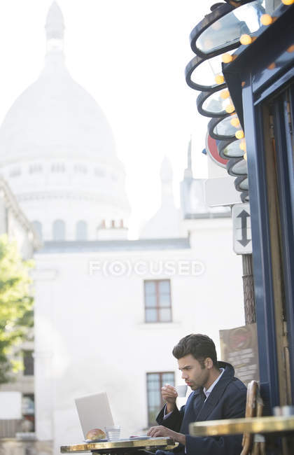 Businessman working at sidewalk cafe near Sacre Coeur Basilica, Paris, France — Stock Photo
