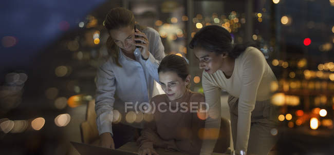 Businesswomen working late at laptop in office at night — Stock Photo