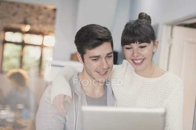 Sourire jeune couple à l'aide d'une tablette numérique — Photo de stock