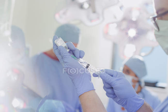 Anestesiologista masculino com seringa preparando o medicamento para anestesia na sala de cirurgia — Fotografia de Stock