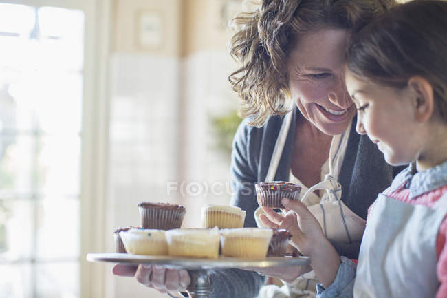 Grand-mère offrant cupcakes petite-fille — Photo de stock