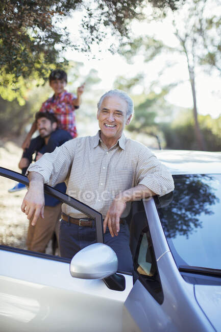 Portrait of confident senior man leaning against car — Stock Photo