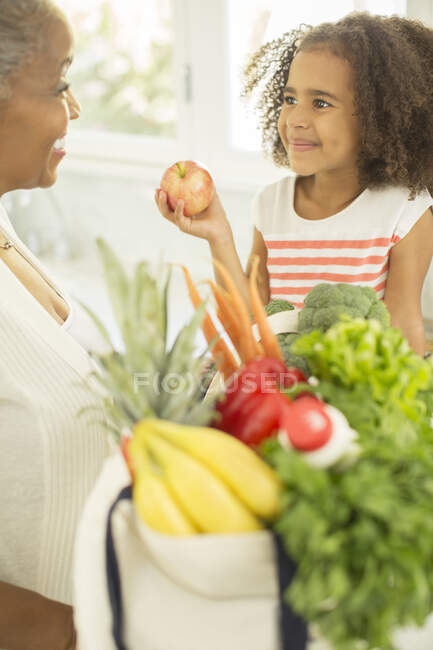 Abuela y nieta desempacando comestibles - foto de stock