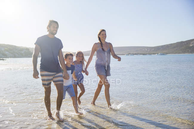 Familia caminando juntos a lo largo de la orilla - foto de stock