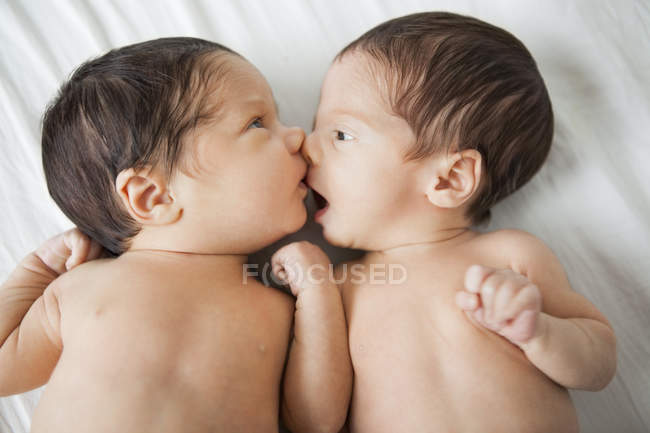 Twin adorable baby girls kissing on bed — Stock Photo