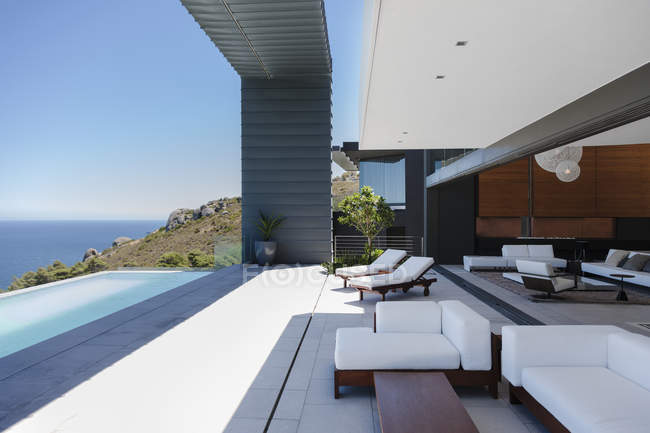 Liegestühle und Infinity-Pool auf der modernen Terrasse mit Blick auf das Meer — Stockfoto