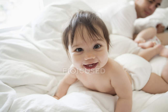 Baby girl crawling in bedsheets — Stock Photo