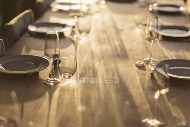 Reflexão ensolarada sobre colocações na mesa de jantar de madeira — Fotografia de Stock