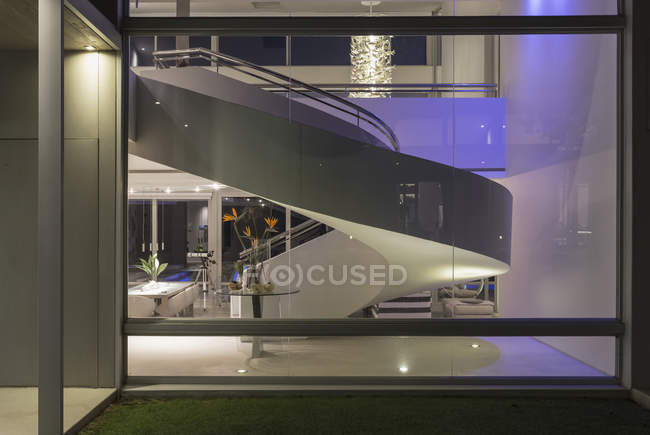 Освещённая винтовая лестница в современном роскошном интерьере дома — стоковое фото
