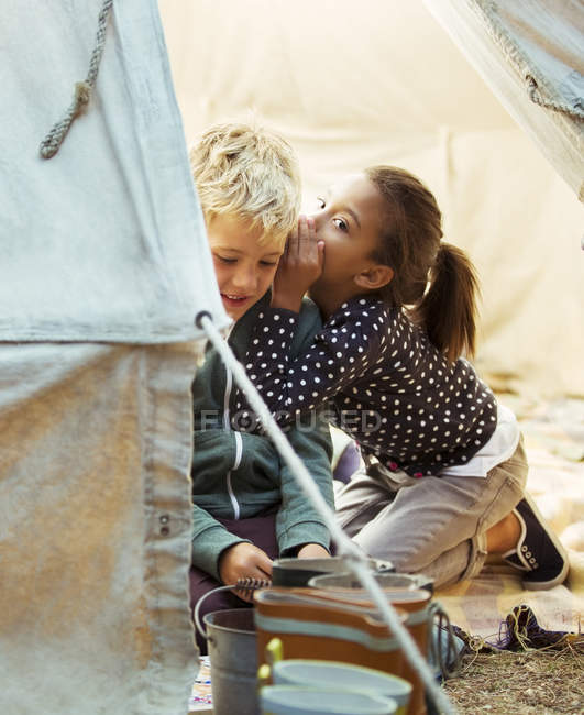 Crianças sussurrando na tenda no acampamento — Fotografia de Stock
