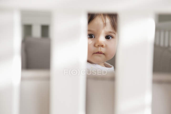 Bébé fille assis dans la crèche — Photo de stock