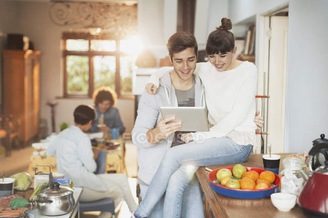 Улыбающаяся молодая пара с помощью цифрового планшета на кухне — стоковое фото