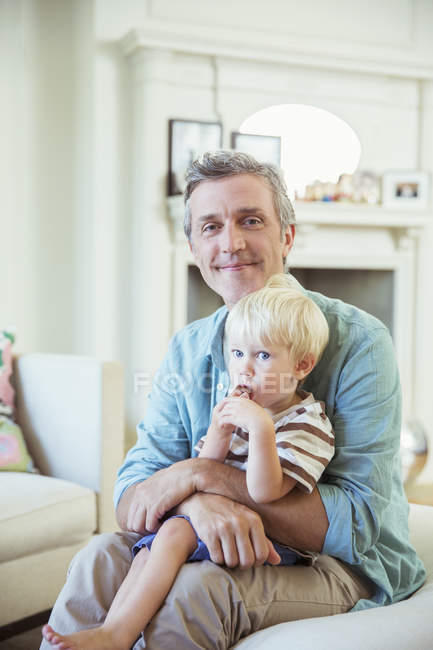Père tenant son fils dans le salon — Photo de stock