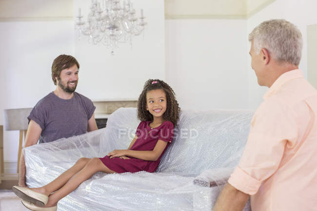 Família carregando sofá com a menina sentada no topo — Fotografia de Stock