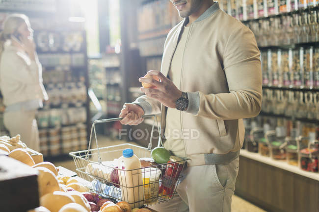 Young man grocery shopping, examining fruit in market — Stock Photo