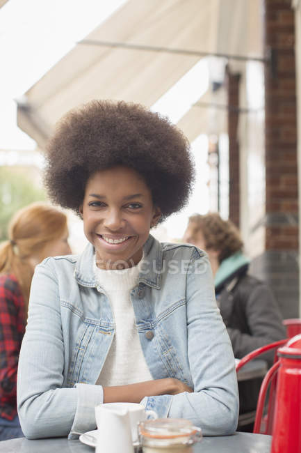 Woman drinking cup of coffee at sidewalk cafe — Stock Photo
