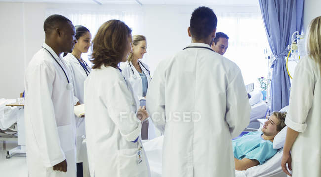 Médico y residentes examinando paciente en habitación de hospital - foto de stock