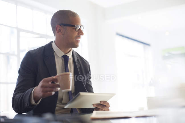 Бизнесмен, использующий цифровые планшеты и пьющий кофе — стоковое фото