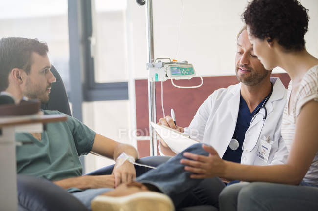 Doctor questioning patient and writing on clipboard — Stock Photo