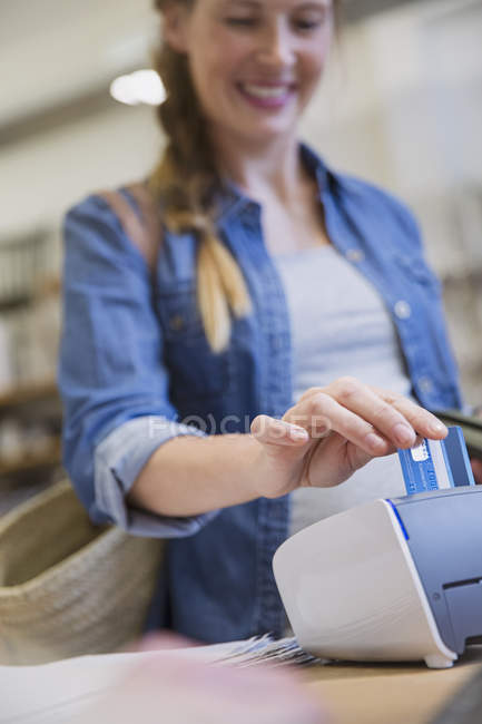 Comprador feminino usando leitor de cartão de crédito na loja — Fotografia de Stock