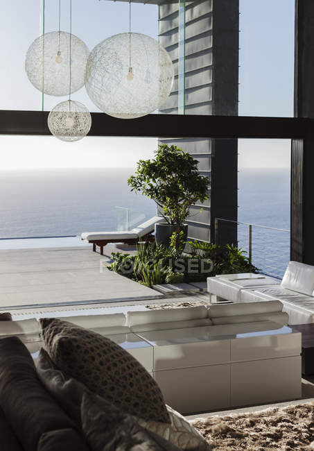 Дивани і столи в сучасній вітальні з видом на океан — стокове фото