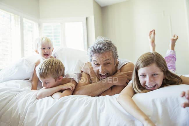 Pai e filhos relaxando na cama — Fotografia de Stock