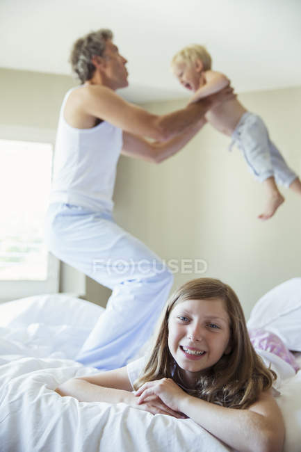 Padre e figli che giocano sul letto — Foto stock