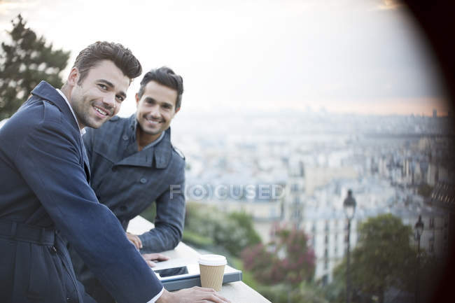 Uomini d'affari che sorridono alla ringhiera con vista su Parigi, Francia — Foto stock