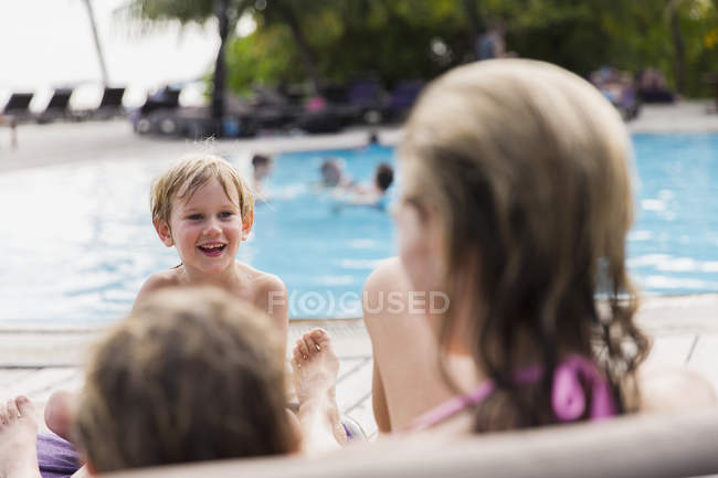 Madre e hijos relajándose junto a la piscina - foto de stock