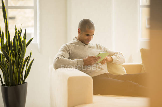 Улыбающийся бизнесмен с помощью цифрового планшета на диване — стоковое фото