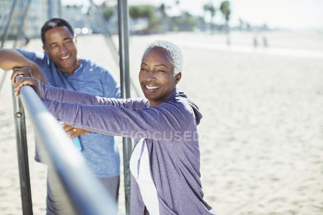 Retrato de casal sênior apoiando-se no bar no parque infantil da praia — Fotografia de Stock
