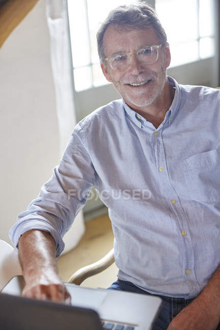 Портрет улыбающийся пожилой человек с помощью ноутбука — стоковое фото