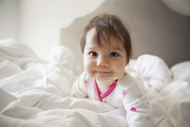 Bebê menina rastejando em lençóis — Fotografia de Stock