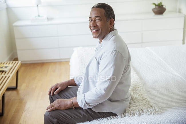 Portrait of smiling senior man sitting at the edge of bed — Stock Photo