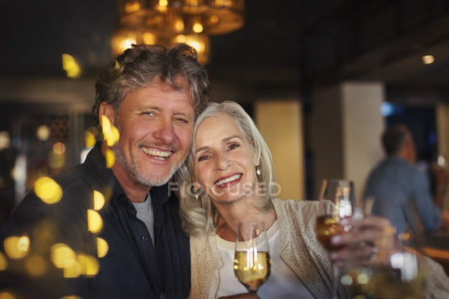 Retrato sorrindo casal sênior brindando copos de vinho branco no bar — Fotografia de Stock