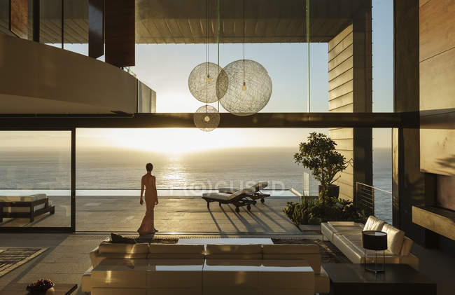 Femme dans la maison moderne donnant sur l'océan — Photo de stock