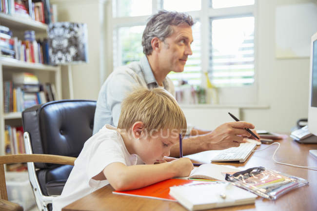 Батько і син працює в домашньому офісі — стокове фото