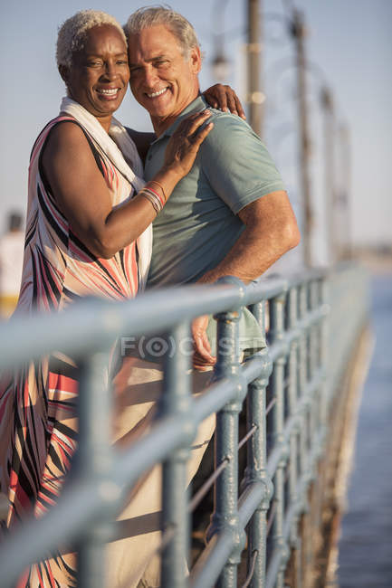 Portrait de couple de personnes âgées souriantes serrant dans leurs bras sur la jetée — Photo de stock