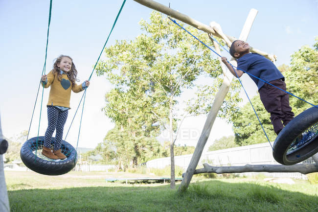 Children playing on tire swings — Stock Photo