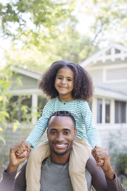 Portrait of smiling father carrying daughter on shoulders — Stock Photo