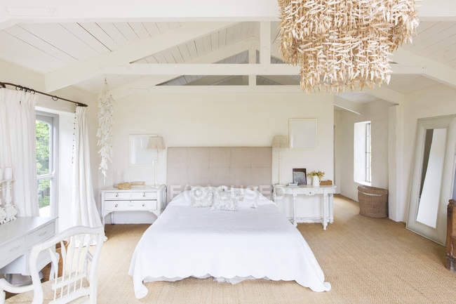 Люстра и кровать в деревенской спальне — стоковое фото