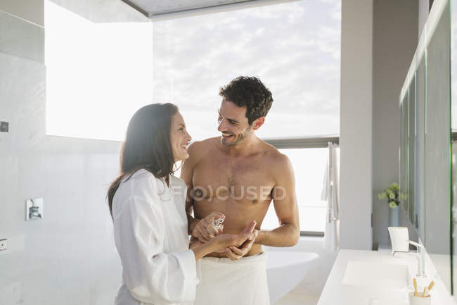 Man dispensing moisturizer in woman hand in home — Stock Photo