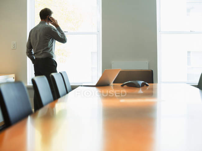 Businessman talking on cell phone in conference room — Stock Photo