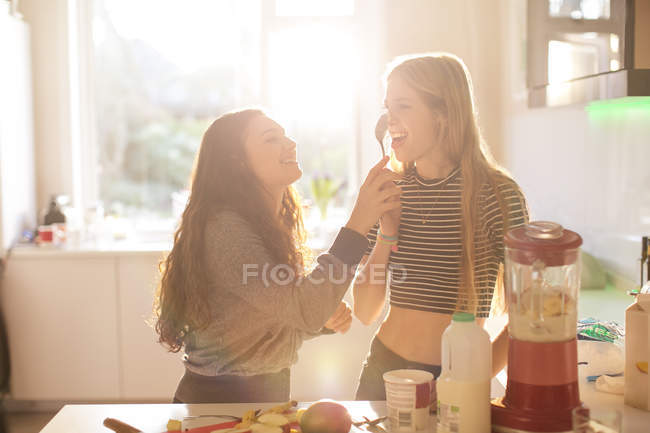 Дівчата-підлітки грають з ложкою на сонячній кухні — стокове фото