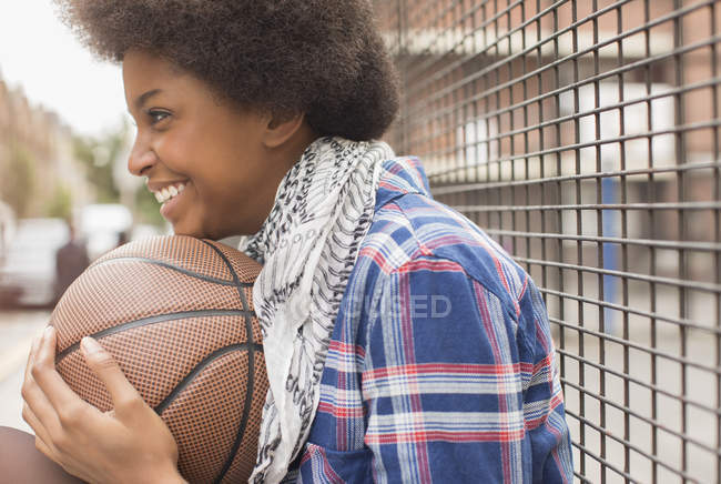 Щаслива молода жінка тримає баскетбол на відкритому повітрі — стокове фото